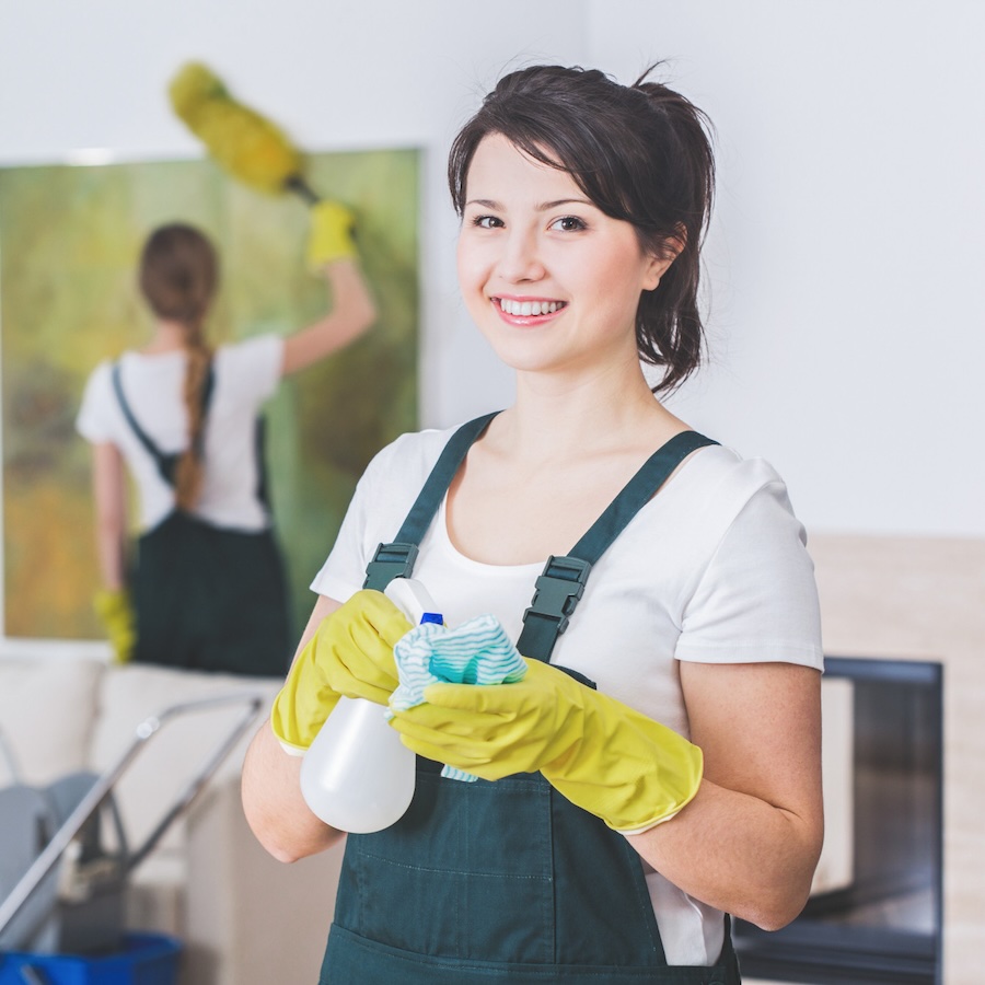 Group of young, hard-working professional cleaners in dirty apartment. Woman with cleaning solution and cloth against blurred background